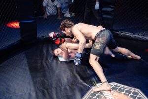 Two MMA fighters grappling against the cage during a Fight Island Championship match in Mallorca