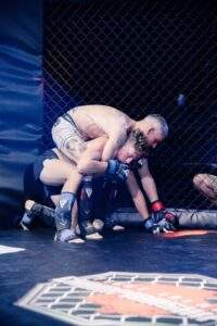 Two MMA fighters grappling against the cage during a Fight Island Championship match in Mallorca