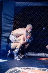 Two MMA fighters grappling against the cage during a Fight Island Championship match in Mallorca