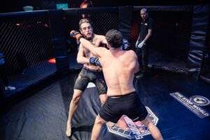 Two MMA fighters grappling against the cage during a Fight Island Championship match in Mallorca