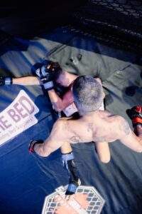 Two MMA fighters grappling against the cage during a Fight Island Championship match in Mallorca