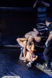 Two MMA fighters grappling against the cage during a Fight Island Championship match in Mallorca