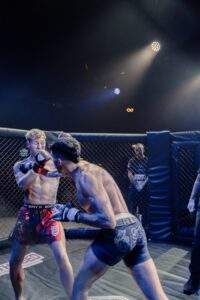 Two MMA fighters grappling against the cage during a Fight Island Championship match in Mallorca