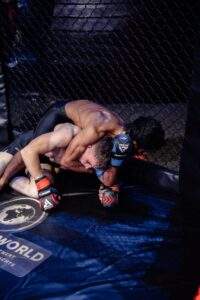 Two MMA fighters grappling against the cage during a Fight Island Championship match in Mallorca