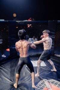 Two MMA fighters grappling against the cage during a Fight Island Championship match in Mallorca