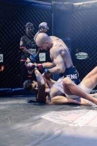Two MMA fighters grappling against the cage during a Fight Island Championship match in Mallorca