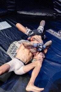 Two MMA fighters grappling against the cage during a Fight Island Championship match in Mallorca