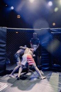 Two MMA fighters grappling against the cage during a Fight Island Championship match in Mallorca