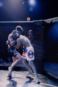 Two MMA fighters grappling against the cage during a Fight Island Championship match in Mallorca