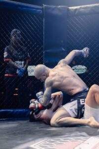 Two MMA fighters grappling against the cage during a Fight Island Championship match in Mallorca